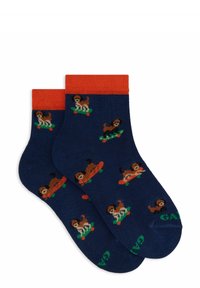 Navy socks with orange cuffs featuring a repeated pattern of colorful dogs on skateboards. Text "GAP" in green on the sole. Knit texture.