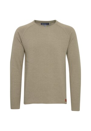 Long-sleeve crew neck shirt in light beige, textured fabric. Features raglan sleeves and a small brand tag at the lower hem.