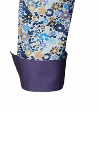Camicia a maniche con stampa floreale in tessuto leggero con fiori blu, neri e arancioni. Caratterizzata da un polsino viola a contrasto.