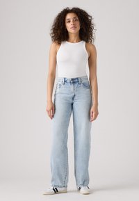 Világoskék, széles szárú farmerdzseki denimből, párosítva fehér bordázott trikóval és fehér cipőkkel fekete csíkokkal. Egyszerű és lezser stílus.