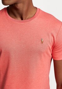 Korale t-shirt z miękkiej tkaniny z okrągłym dekoltem, z małym haftowanym logo w kontrastowych kolorach na piersiach.