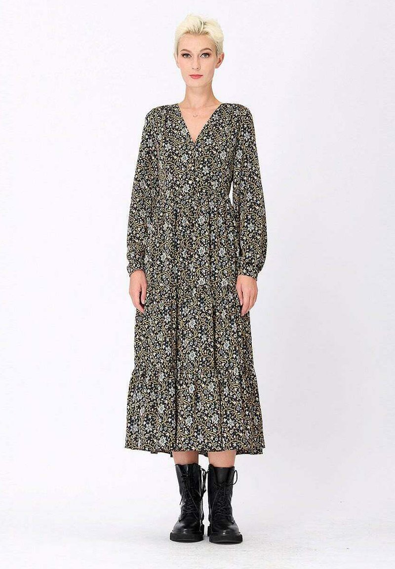 Robe à manches longues à motifs floraux noirs, avec un décolleté en V, un design à volants et des poignets élastiques, associée à des bottes en cuir noires à lacets.