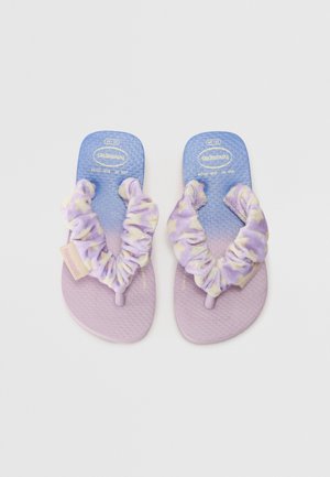 Lila Flip-Flops mit strukturierten Sohlen, ausgestattet mit einem weichen, batikfarbenen Stoffriemen in Lila und Gelb sowie einem kleinen Markenetikett an der Seite.