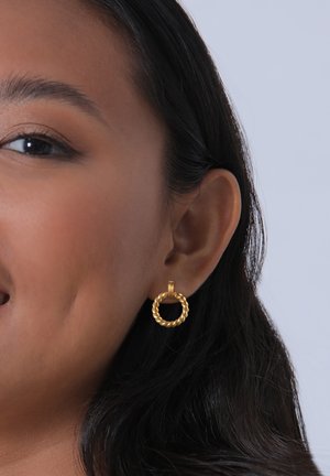 Pendientes de aro dorados con un diseño retorcido. Tamaño pequeño con un mecanismo de cierre suave, textura visible y un acabado brillante.