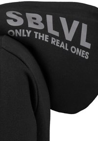 Schwarzer Hoodie aus einem weichen, strukturierten Stoff. Die Kapuze zeigt in einer gewölbten Gestaltung den markanten grauen Text: "SBLVL ONLY THE REAL ONES".