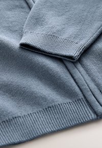 Maglione blu a maglia con polsini e orlo a coste, tessuto testurizzato con una finitura morbida e un design semplice e senza ornamenti.