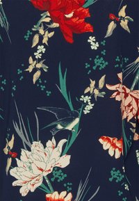 Tecido azul-marinho com padrões florais vibrantes em vermelho, branco e verde, com a silhueta de um pássaro entre várias flores e folhas.