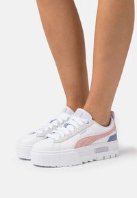 Hvite plattformsneakers med lilla og rosa aksenter, med strukturert stripe, snørelukking og solid såle.