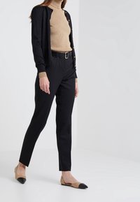 Svart kavaj med guldknappar, beige ribbad polotröja, svart bälte, skräddarsydda svarta byxor och tvåfärgade beiga och svarta ballerina.