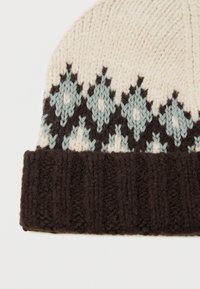 Neulottu hattu, jossa on vaalea pääosa, sinisiä ja tummanruskeita timantti-kuvioita sekä paksu, ribattu ruskea reunus alaosassa.