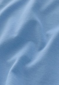 Tissu en coton bleu clair avec une texture lisse, présentant un motif à fines côtes. Le matériau est doux et légèrement froissé.
