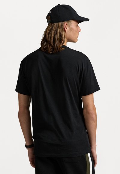 Tricou negre din bumbac, cu o croială lejeră, mâneci scurte și guler rotund, asortat cu o șapcă neagră. Material texturat și design casual.