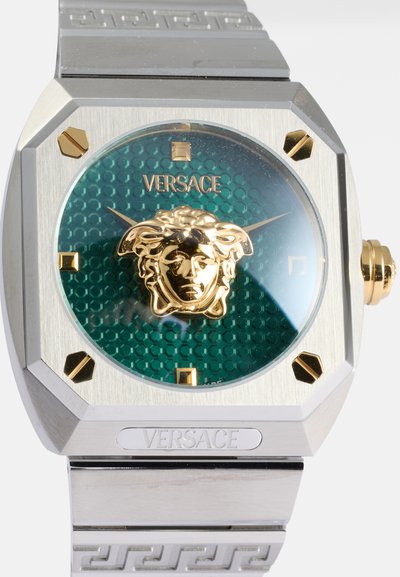 Reloj octagonal de Versace con un dial en patrón hexagonal color turquesa, emblema de la Medusa en oro, acentos dorados y una pulsera de acero inoxidable.