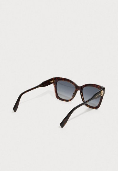 Skildpaddemønstrede firkantede solbriller med mørke gradientlinser og guldfarvede logo-detaljer på stængerne.
