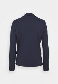 Blazer bleu marine cintré, vu de dos, avec manches longues et col cranté sur fond blanc uni.