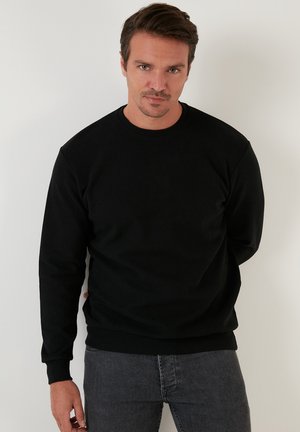 Zwarte sweatshirt gemaakt van een katoenmix. Heeft een ronde hals, lange mouwen en ribgebreide boorden en onderkant, wat zorgt voor een eenvoudig, casual ontwerp.