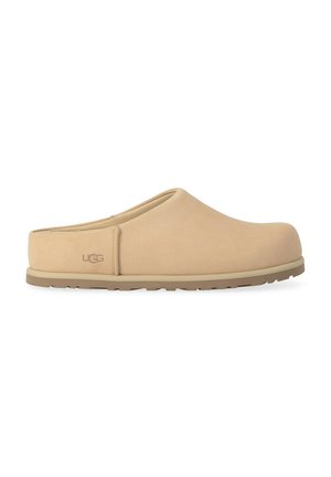 Mule beige UGG slip-on con punta chiusa e arrotondata e suola piatta in gomma, progettata per un utilizzo casual sia indoor che outdoor.