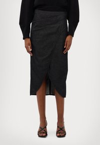 Mörk denimmidi kjol med en omlottdesign, som har vinklade fållar och en mjuk textur. Kombinerad med svarta remsandaler.