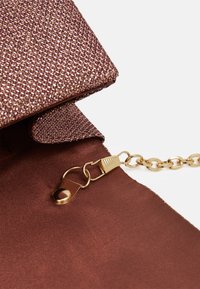 Clutch rosa metallizzato con superficie tessuta e testurizzata. Dotata di tracolla a catena dorata e chiusura a patta magnetica per un accesso sicuro.