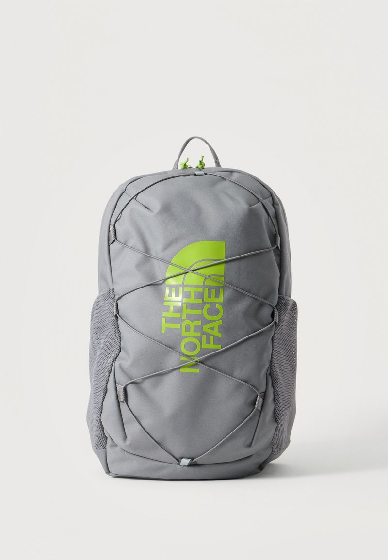 Γκρι σακίδιο North Face με λογότυπο λάιμ πράσινο, μπροστινό λάστιχο bungee, δίχτυα πλαϊνές τσέπες και επάνω χειρολαβή σε απλό φόντο.