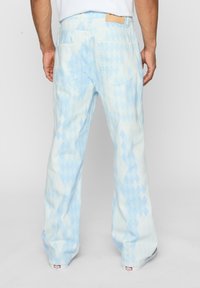 Light blue flared jeans featuring a diamond pattern in varying shades, with two back pockets and a leather tag at the waistband.