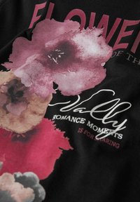 Schwarzer Stoff mit einem großen floralen Grafikdesign in den Farben Pink und Lila, mit weißem Text, der "Vally Romance Moments Is For Sharing" lautet.