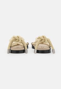 Sandali in corda beige con cinturini annodati, plantare in pelle scamosciata marrone chiaro, suola nera e dettagli in metallo argento sulle estremità dei cinturini.