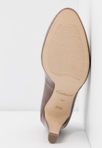 Semelle de chaussure à talons en cuir marron affichant la taille 4½, marque "Gabor", "Fabriqué au Portugal", et motif de grip texturé.