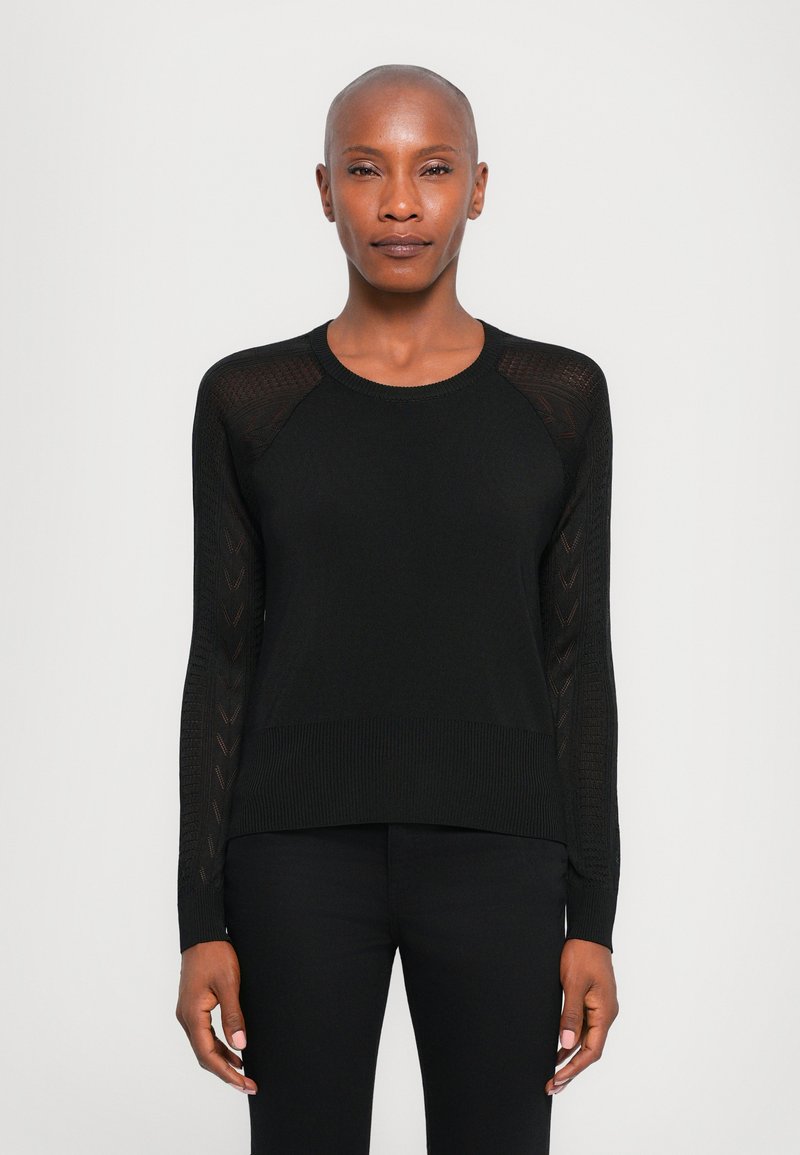 Musta neulepaita, jossa on pyöreä kaula-aukko, teksturoituneet hihat, joissa on viuhkamallinen kuvio, ja ribbireunus alhaalla. Slim fit -malli.