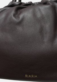 Bolso de mano de cuero marrón oscuro con un acabado texturizado, que presenta un diseño fruncido y el logo dorado "BIASIA" cerca de la base.