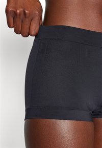 Black athletic shorts with a smooth elastic waistband, featuring flat seams and a fitted design, highlighting a breathable fabric texture.