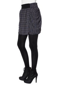 Minifalda negra con cintura elástica, fabricada con un tejido estampado en azul marino y beige, que presenta detalles drapeados y se combina con botas altas de tacón negras.