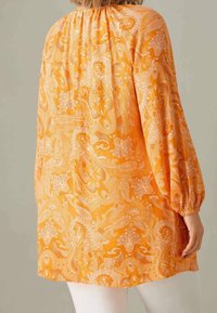 Blusa naranja con un patrón de paisley, escote fruncido y mangas abullonadas. Hecha de una tela ligera, con un corte relajado y una textura sutil.