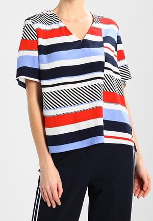 Top de manga corta con cuello en pico, fabricado en tejido ligero con rayas horizontales en rojo, azul marino, azul claro y blanco, incluyendo detalles en negro.