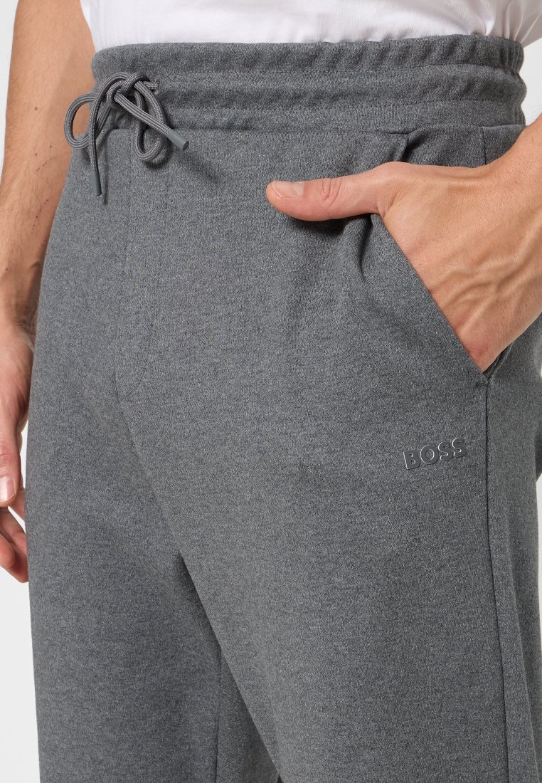 Pantalon grigi in felpa realizzati in morbido tessuto, dotati di vita elastica con cordoncino, tasche laterali e un sottile dettaglio del logo sulla gamba sinistra.