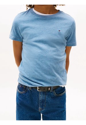 Lyseblå kortærmet T-shirt med rund halsudskæring, stylet med mørkeblå denimjeans og et sort bælte med en sølvfarvet spænde.