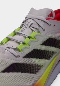 Letvægtsløbesko i grå og neongrøn. Har sorte stribede accenter, tekstureret mesh-overdel og en levende sålgradient.