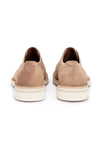 Scarpe scamosciate color beige con un profilo basso, forma arrotondata e suola in gomma bianca con sottili strisce grigie lungo il fondo.