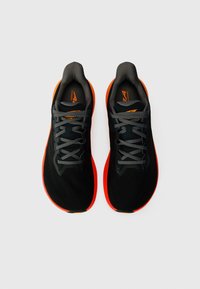 Sorte løbesko med orange detaljer, der har en tekstureret overdel, grå snørebånd og gummisåler. Rund tå og polstret krave-design.