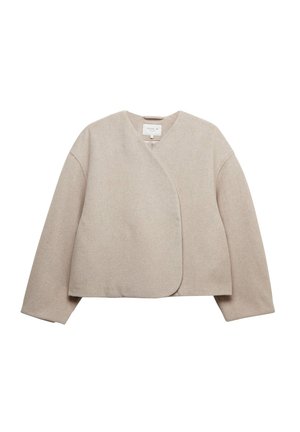 Beige kääntötyylinen takki, joka on valmistettu pehmeästä kankaasta, jossa on V-pääntie, pitkät hihat ja minimalistinen muotoilu ilman kiinnityksiä tai koristeluita.