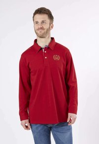 Polo rouge à manches longues en coton, avec un col, trois boutons, logo brodé sur la poitrine gauche et fentes sur les côtés.