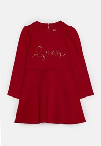 Rotes langärmliges Kleid mit rundem Ausschnitt, gefälteltem Taillenbund und dekorativem Text, der an der Vorderseite mit Edelsteinen verziert ist. Reißverschluss hinten.