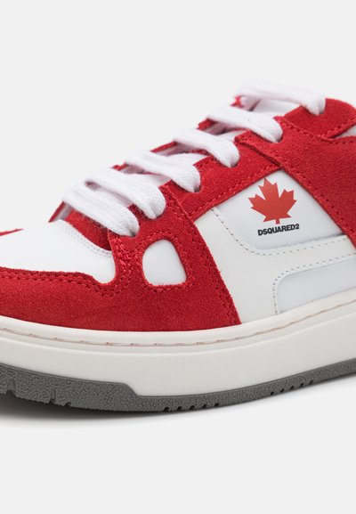 Zapatillas rojas y blancas hechas de ante y cuero, con un logo de hoja de arce canadiense, cordones blancos y una suela de goma con acentos grises.