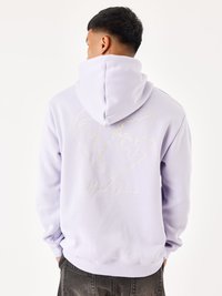 Sudadera morada con un gráfico en forma de corazón dorado que presenta un mapa del mundo en la parte posterior. Hecha de una tela suave, tiene una capucha grande.