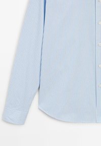 Lyseblå og hvide stribet skjorte med lange ærmer, knaplukning og afrundet kant. Fremstillet af glat stof med en sprød tekstur.