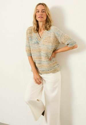 Beige and blue striped knit sweater with a V-neck, short sleeves, and ribbed hem, paired with white wide-leg trousers.