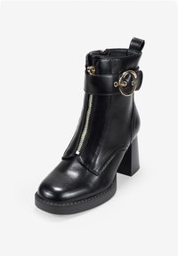 Stivale alla caviglia in pelle nera con cerniera laterale, punta tonda, tacco largo e un anello decorativo dorato sulla cinghia. Texture liscia, design minimalista.