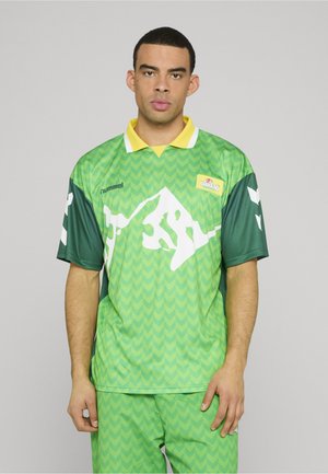 Grøn og gul sportstrøje med chevron-mønster, korte ærmer og en hvid bjerggrafik. Kombineret med matchende grønne shorts.