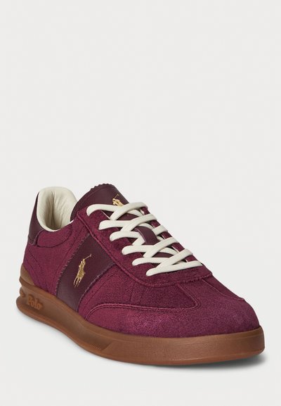 Low-top burgundy suede sneaker with leather panel, white laces, brown rubber sole, and gold Polo logo on side and tongue.