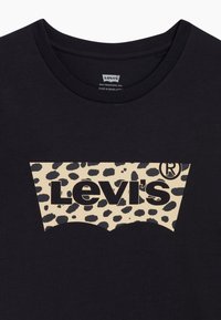 Czarny bawełniany T-shirt z dużym beżowym nadrukiem w panterę z logo Levi's. Klasyczny okrągły dekolt, gładka tekstura materiału.